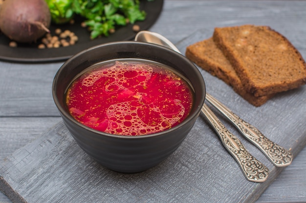 Bortsch, spu ukrainien traditionnel. Soupe de légumes à la crème sure dans une tasse en céramique noire.