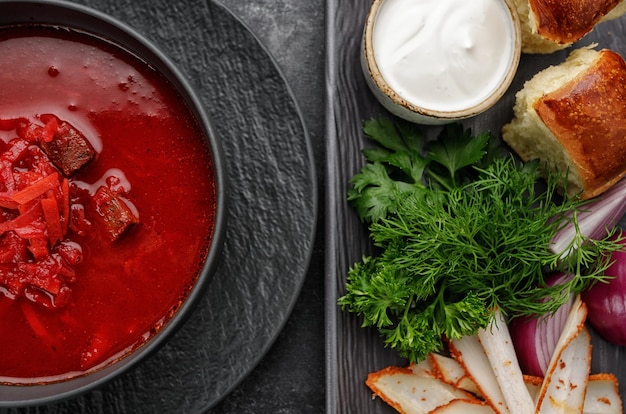 Bortsch ukrainien avec beignets crème sure et aneth sur fond sombre