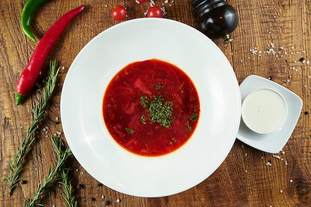 Bortsch ukrainien fait maison et savoureux avec de la crème sure et du canard dans un bol sur une surface en bois. Cuisine ukrainienne. Copiez la photographie alimentaire de l'espace. soupe rouge