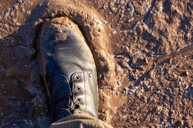 Botte de l'armée dans la boue humide vue de dessus en gros plan avec mise au point sélective à la lumière du jour