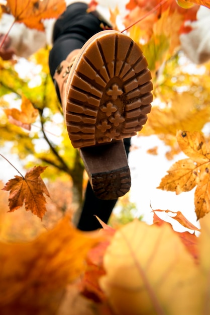 Botte femme marche sur les feuilles d'automne vue bottomup Gros plan d'une femme marchant sur les feuilles