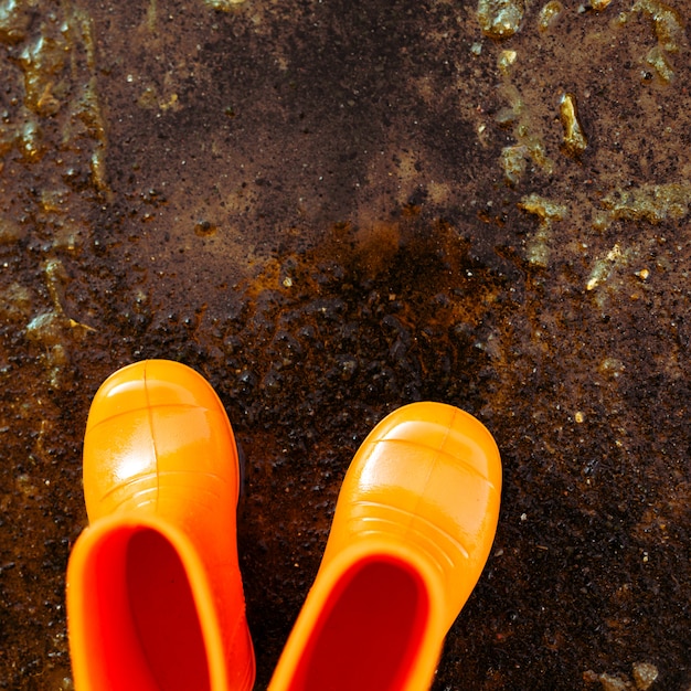 Bottes en caoutchouc orange debout à côté de la flaque d&#39;eau.