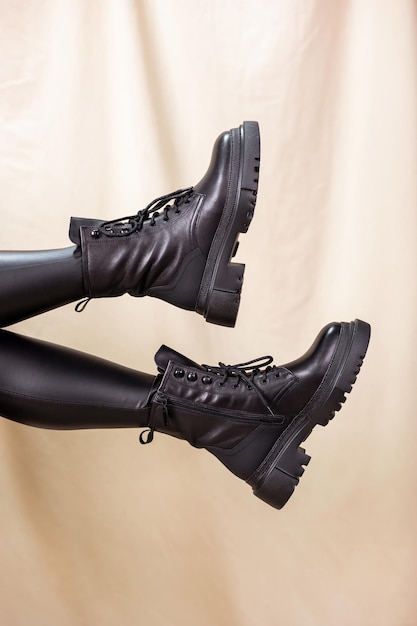 Bottes en cuir noir d'hiver pour femmes avec des jambes sur un fond de studio. Nouvelle collection de chaussures pour dames élégantes