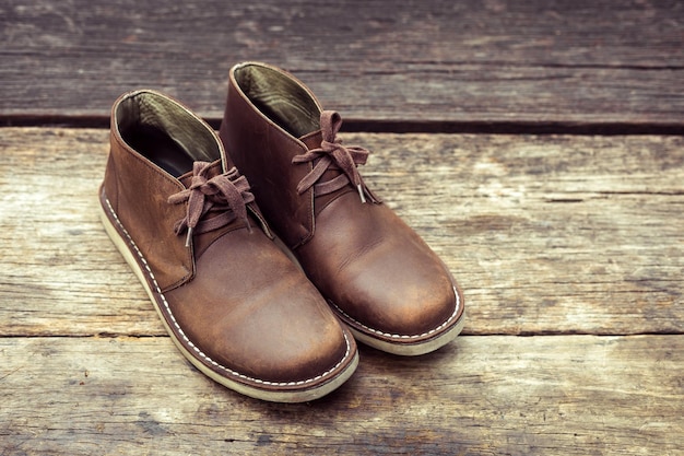 Photo bottes élégantes brunes sur la couleur rétro de fond en bois