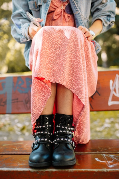 Bottines en cuir noir pour femme avec sangles, clous en métal et fermeture éclair, tourné dans un banc avec des graffitis dans la rue.