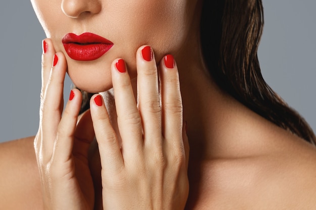 Bouche et ongles féminins avec manucure rouge et rouge à lèvres.
