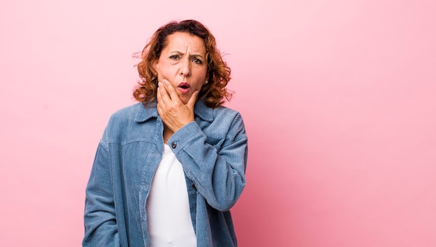 Photo avec la bouche et les yeux grands ouverts et la main sur le menton se sentant désagréablement choqué en disant quoi ou wow