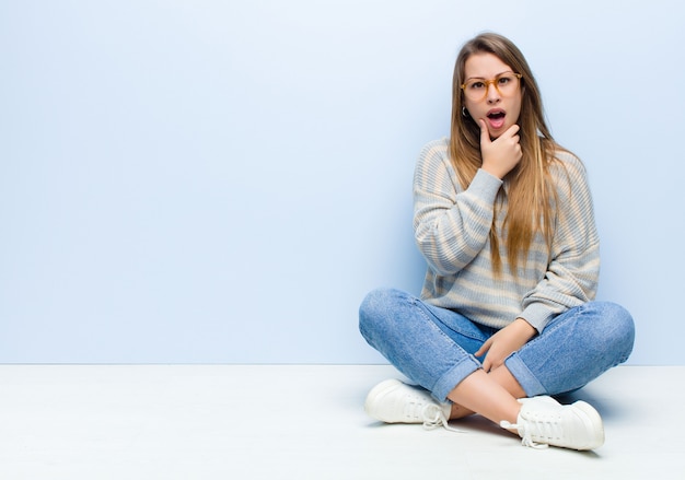 avec la bouche et les yeux grands ouverts et la main sur le menton, se sentant désagréablement choqué, disant quoi ou wow