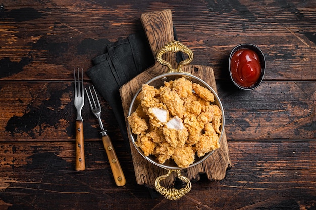 Bouchées de poulet au maïs soufflé croustillant maison dans une poêle Fond en bois Vue de dessus