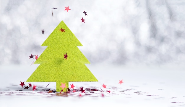 Bouchent arbre de Noël vert avec une étoile rouge étincelant tombant sur un sol blanc à la lumière de bokeh fond argenté