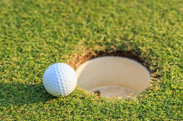 Bouchent la balle de golf sur la lèvre de la coupe dans le cours