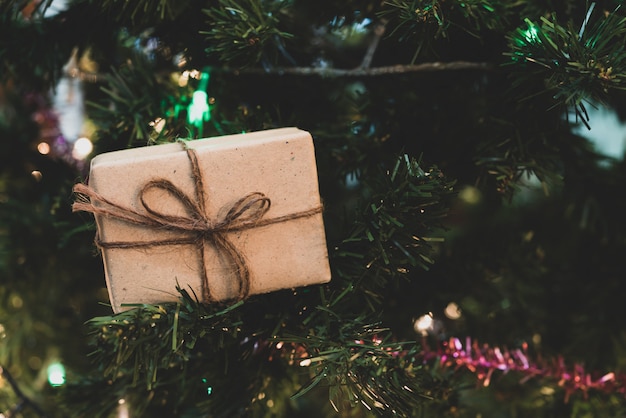 Bouchent la boîte de cadeau de Noël sur le pin avec ruban et éclairage