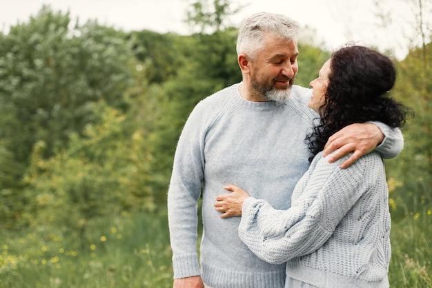 Bouchent un couple romantique debout dans un parc en automne et s'embrassant dans la journée. Homme et femme portant des pulls bleus. La femme est brune et l'homme est gris.