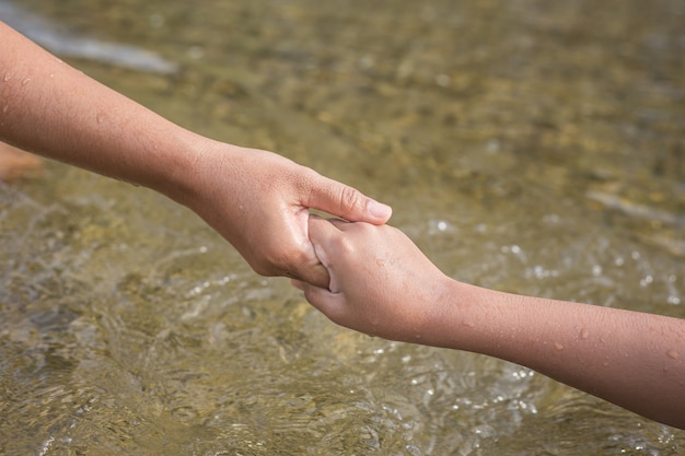 Bouchent la femme tenant sa main de la fille dans la rivière. Concept d&#39;aide