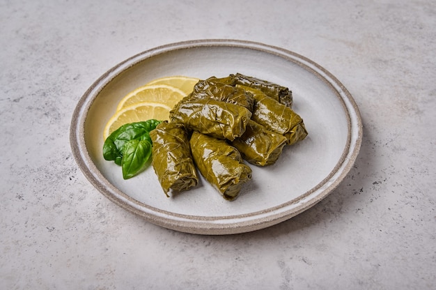 Bouchent les feuilles de vigne farcies au dolma avec du riz, du persil et du citron sur une plaque lumineuse