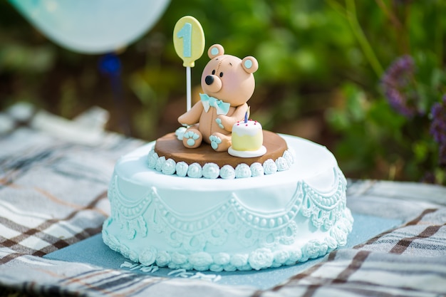 Bouchent le gâteau incroyable pour le premier anniversaire du garçon. Couleurs bleues et blanches avec ourson de mastic à sucre