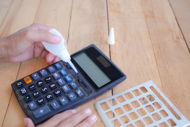 Bouchent la goutte de colle pour la calculatrice de réparation sur le concept d'entreprise de fournitures de bureau de fond en bois