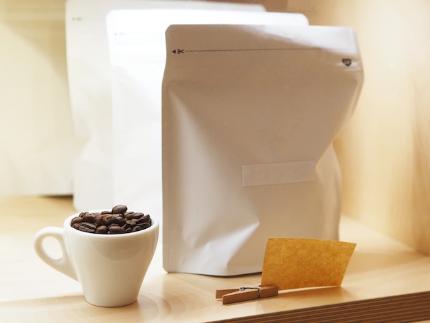 Bouchent les grains de café torréfiés dans des sacs à fermeture à glissière en papier et en papier blancs