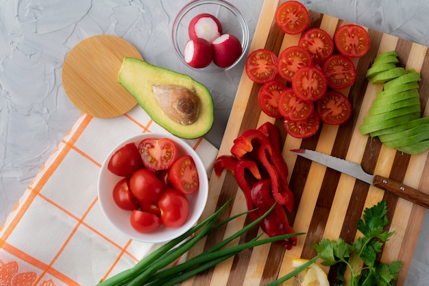 Bouchent les légumes tranchés organiques frais poser sur la planche à découper, tomate, avocat, poivrons