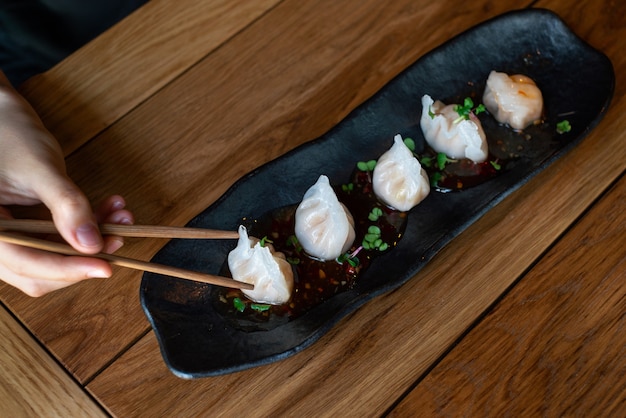 Bouchent la main féminine avec des boulettes chinoises chaudes dimsum chinois cuits à la vapeur avec des baguettes vue de dessus