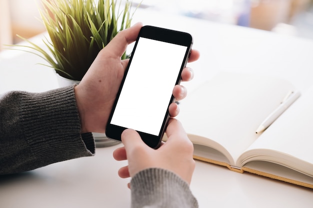 Bouchent la main de femme à l&#39;aide d&#39;un téléphone intelligent avec un écran blanc à la maison.