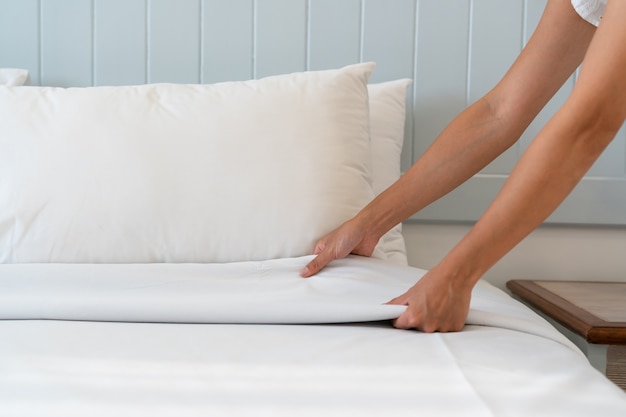 Photo bouchent la main de femme mis en place un drap blanc dans la chambre d'hôtel, copiez l'espace pour le texte.