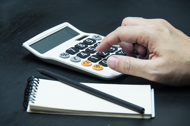 Bouchent La Main De L'homme à L'aide De La Calculatrice Sur Fond De Bureau En Bois.