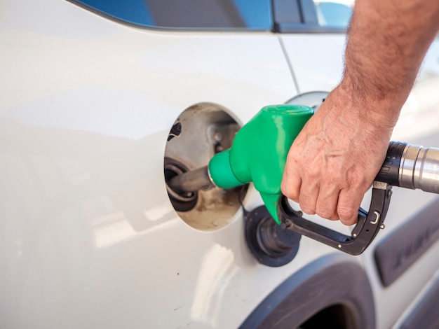 Bouchent la main de l'homme remplissant la voiture blanche avec du carburant