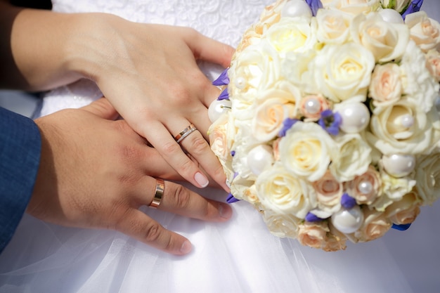 Bouchent les mains des mariés avec bouquet de mariée