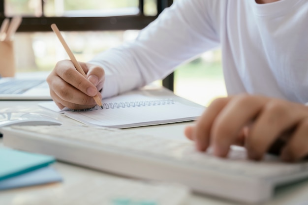 Bouchent les mains avec un stylo écrit sur ordinateur portable.