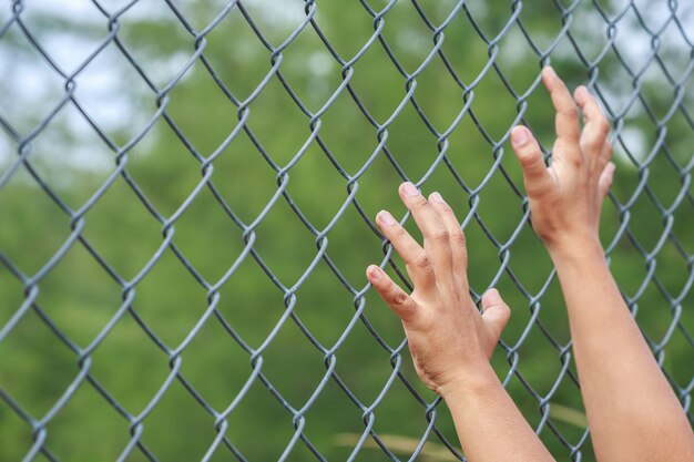 Bouchent les mains suspendues sur une clôture en métal