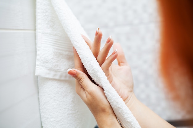 Bouchent les mains utilisent une serviette blanche dans une salle de bain claire