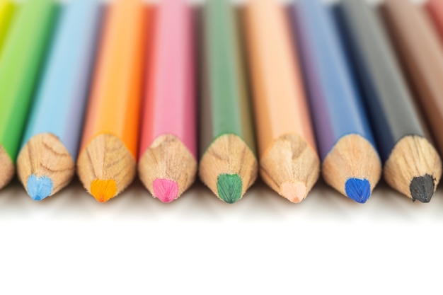 Bouchent la mise au point sélective du crayon de couleur coloré empilé sur blanc