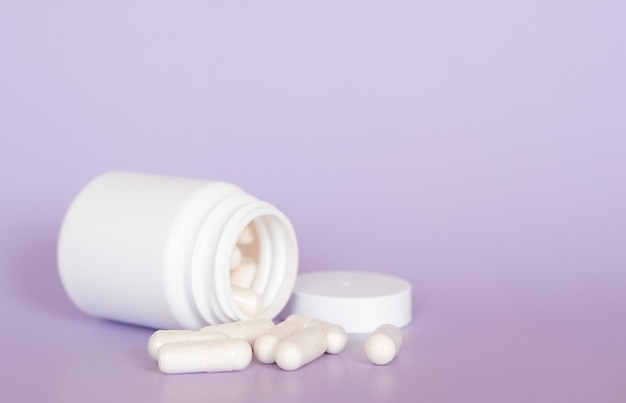 Bouchent les pilules et capsules blanches sur fond violet avec espace de copie. Concentrez-vous sur le premier plan, bokeh doux. Concept de pharmacie pharmacie.