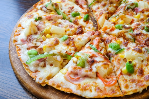Photo bouchent pizza hawaïenne, ananas, bacon et fromage sur la table en bois