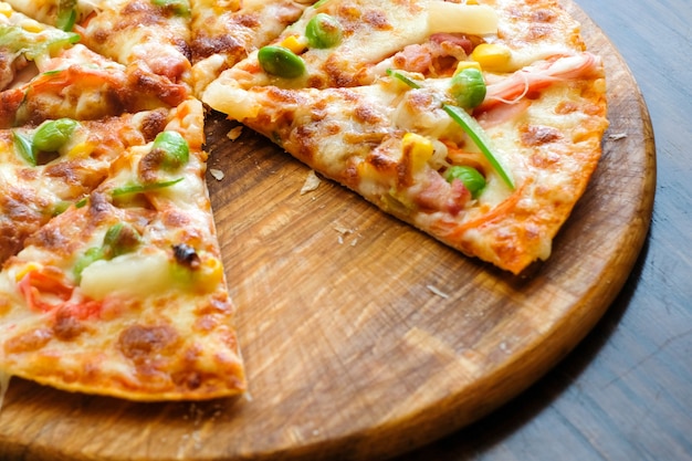 Photo bouchent pizza hawaïenne, ananas, bacon et fromage sur la table en bois