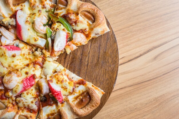 Bouchent la pizza sur une plaque en bois sur le fond de la table