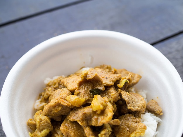 Bouchent le porc au curry rouge avec du riz dans une tasse en mousse