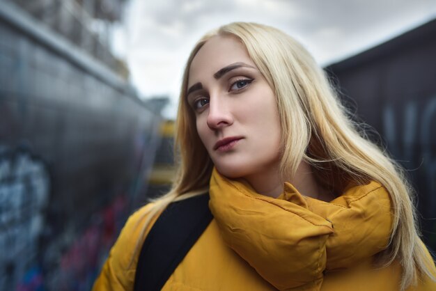 Bouchent le portrait d'une adolescente blonde hipster faisant selfie, elle porte une veste jaune et un sac à dos