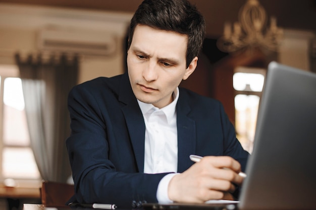 Bouchent le portrait d'un beau jeune designer travaillant assis dans un café.