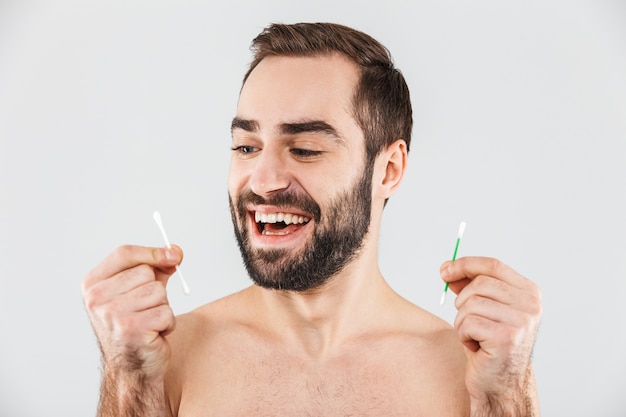 Bouchent le portrait d'un bel homme barbu debout isolé sur blanc, tenant des cotons-tiges