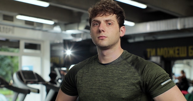 Bouchent le portrait d'un bel homme de remise en forme dans la salle de gym. Muscles entraînement fitness et musculation, concept de mode de vie sain pour le sport confiant.