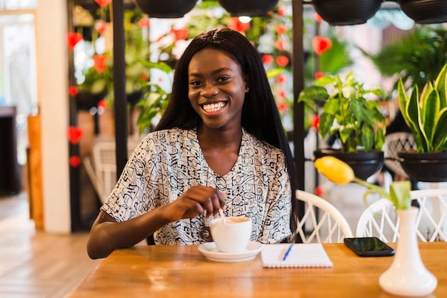 Bouchent le portrait d'une belle femme afro-américaine souriante avec une tasse de café