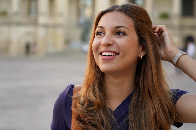 Bouchent le portrait d'une belle femme souriante regardant de côté sur fond urbain