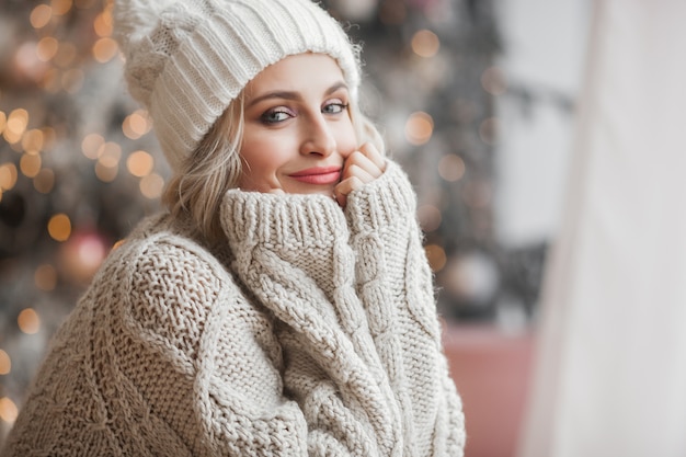 Photo bouchent le portrait de la belle jeune femme sur la scène de noël. jeune fille souriante avec une peau parfaite près de l'arbre de noël.