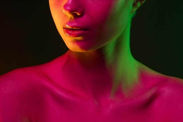 Bouchent le portrait du mannequin féminin en néon sur fond de studio sombre.