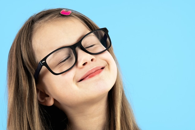 Bouchent le portrait d'une écolière enfant portant des lunettes isolées sur bleu