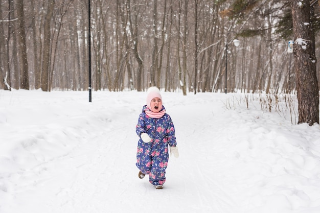 Bouchent le portrait d'un enfant adorable jouant avec de la neige dans le parc