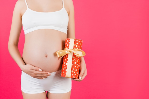 Bouchent portrait de femme enceinte en sous-vêtements blancs tenant une boîte-cadeau