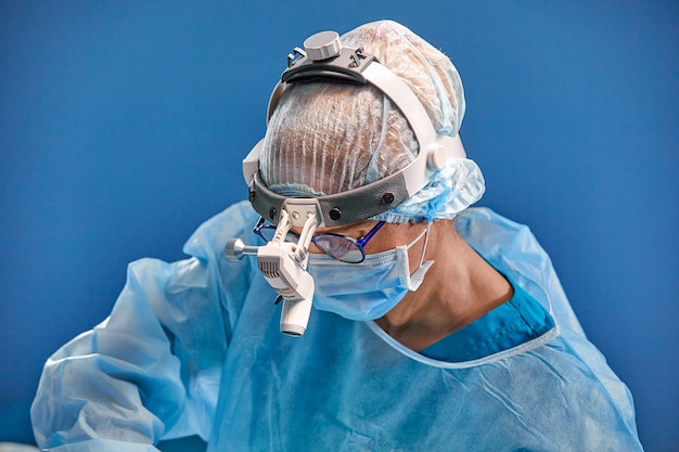 Photo bouchent le portrait de femme médecin chirurgien portant un masque de protection et un chapeau pendant l'opération.